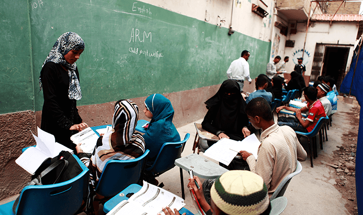 Education in Pakistan lead image: students and teachers in an alleyway classroom