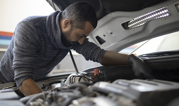 A photograph of a mechanic working on an automobile. 